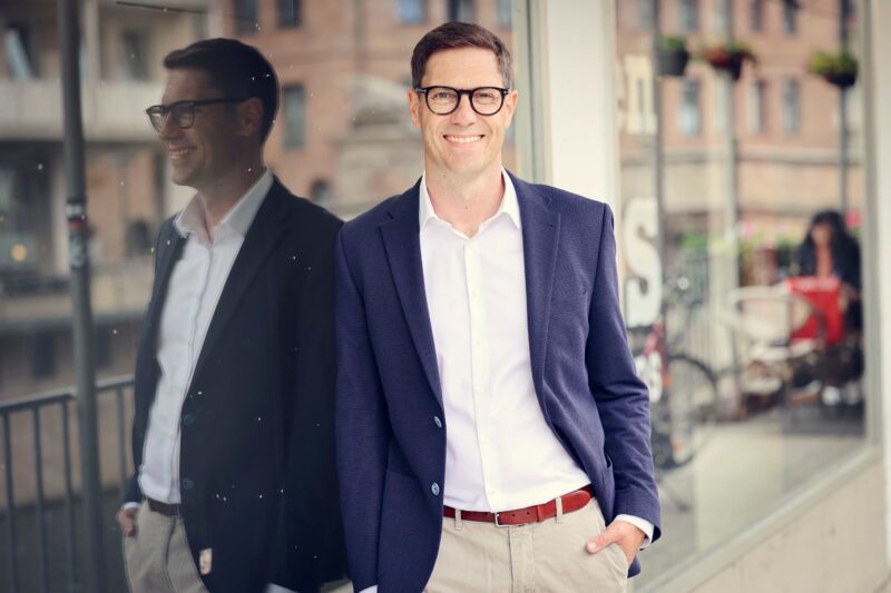 Andreas Dorsch, Interim Manager für Vertrieb, geht lächelnd durch eine Stadtstraße